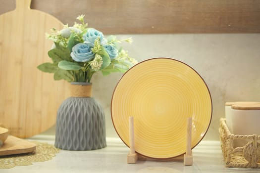 A charming display with a beautiful yellow plate and decorative flowers in a cozy setting