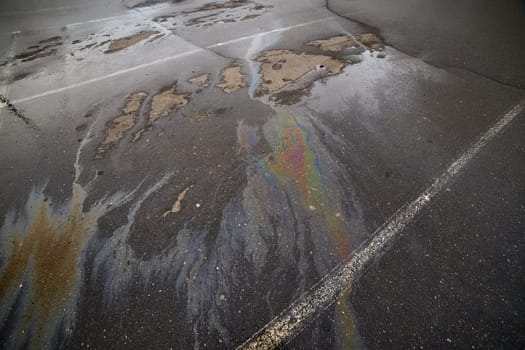 Rainbow oil spill on cracked asphalt, illustrating environmental pollution and urban decay.