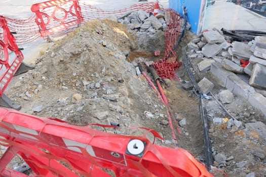 The busy construction site has the excavated area marked with bright red safety barriers
