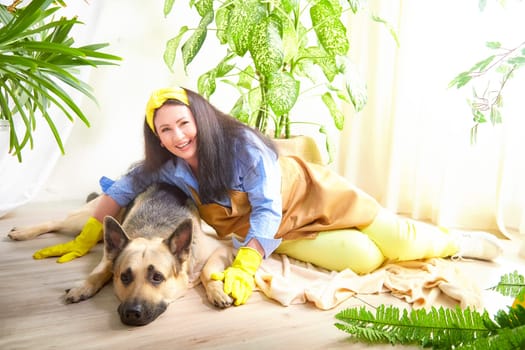 A joyful gardener enjoys quality time with her dog in a blooming greenhouse.