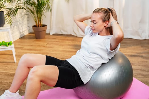 Young woman exercising on a stability ball in a bright room with plants close up