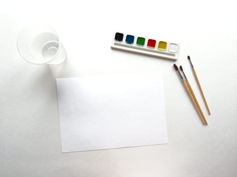 Watercolor set. Blank canvas with paints, brushes, and cup ready for artistic expression.