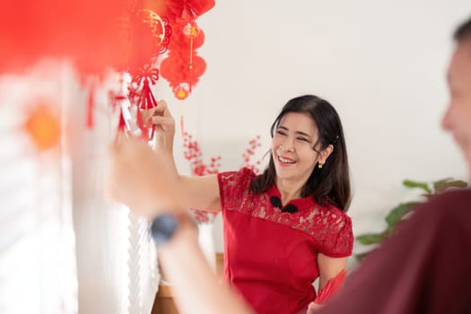 An elderly couple joyfully decorates their home for Chinese New Year embodying cultural traditions.