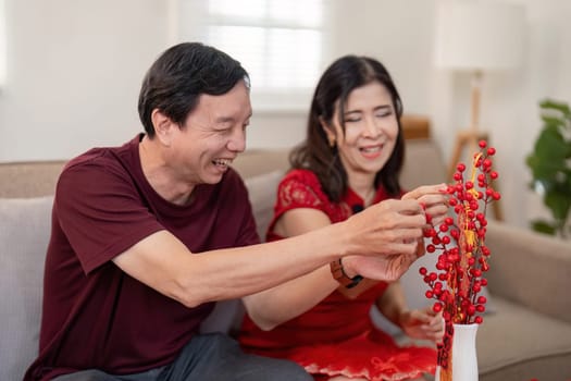 A heartwarming scene of an elderly couple joyfully preparing for Chinese New Year at home sharing traditions and happiness.