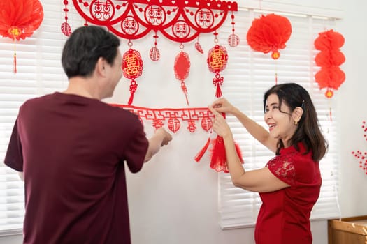 An elderly couple joyfully decorates their home for Chinese New Year celebrating traditions and family togetherness.