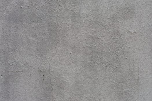 Rough, uneven, old, gray plaster on the wall close-up.