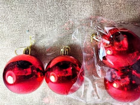 Bright red ornaments sit partially out of their packaging, perfect for festive holiday decorating, enhancing Christmas cheer at home.