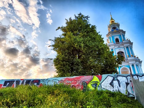 Kostroma, Russia - July 31, 2024: Historic tower of Kostroma stands tall beside colorful street art, showcasing the blend of culture and nature at sunset.