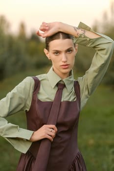 A stylish girl in a dress with a tie in a summer garden. A fashion show in nature.