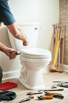 Plumber working on a toilet installation, using tools and focusing on his professional task in a modern bathroom