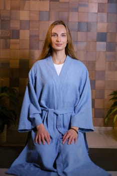 Girl in blue kimano practicing kundalini or qigong yoga in fitness gym . Spiritual energy, life force located at the base of the spine.