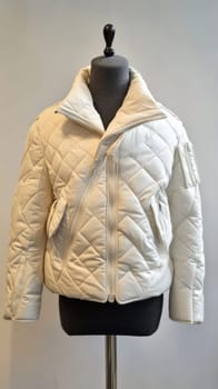 White quilted jacket with asymmetrical zipper and large collar presented on a mannequin