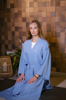 Girl in blue kimano practicing kundalini or qigong yoga in fitness gym . Spiritual energy, life force located at the base of the spine.