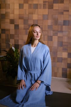 Yoga instructor in blue kimano at fitness gym . The girl does qigong yoga. The exercises are based on the movement of internal energy, the system of channels, energy centers, chakras.