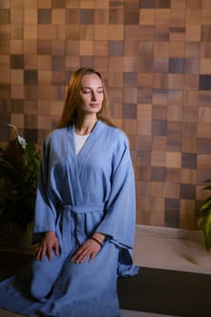 Girl in blue kimano practicing kundalini or qigong yoga in fitness gym . Spiritual energy, life force located at the base of the spine.