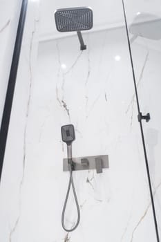 New stylish faucet and shower in shower enclosure with white granite walls. Modern luxury shower cubicle.