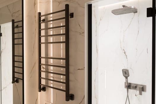 Modern black radiator on white marble wall in bathroom. New bathroom with granite white tiles.
