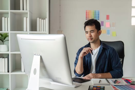 Graphic designer focused on digital projects in a modern studio, surrounded by color samples and design tools.