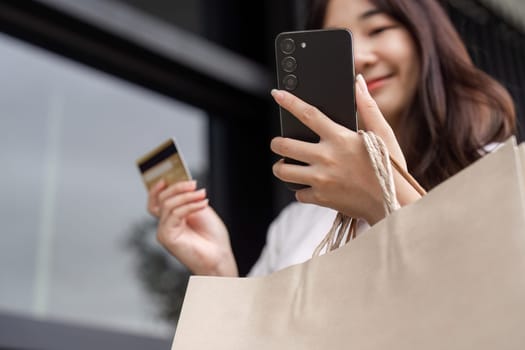 Young woman shopping on Black Friday, holding shopping bags and a credit card, capturing the excitement of seasonal retail deals.
