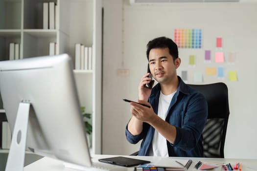Graphic designer in a modern studio using digital tools and color samples for creative projects.