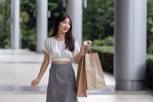 A young woman happily carries shopping bags during a Black Friday sale in a modern city environment.