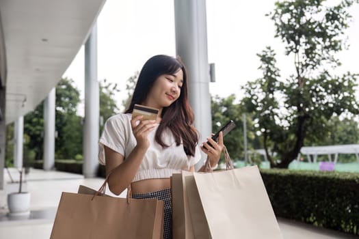 A young woman enjoys Black Friday shopping, holding bags and a credit card, symbolizing retail excitement and holiday deals.