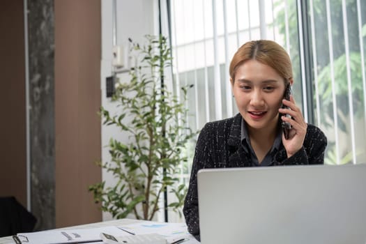 Businesswoman in office analyzing graphs on a laptop, focusing on financial data for strategic planning.