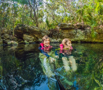 09.12.24, Playa Del Carmen, Mexico: Father and son tourists in the water of a cenote at Xcaret park wearing marked life jackets. Mexican tourism in natural parks. Family bonding, eco-tourism, and adventure concept in Quintana Roo.