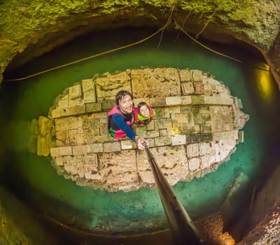 09.12.24, Playa Del Carmen, Mexico: Father and son tourists in the water of a cenote at Xcaret park wearing marked life jackets. Mexican tourism in natural parks. Family bonding, eco-tourism, and adventure concept in Quintana Roo.