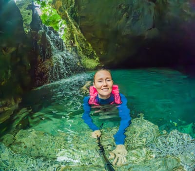 09.12.24, Playa Del Carmen, Mexico: Woman tourist in the water of a cenote at Xcaret park wearing a marked life jacket. Mexican tourism in natural parks. Adventure, relaxation, and eco-tourism concept in Quintana Roo.