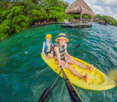Mother and son tourists kayaking together on the crystal-clear turquoise waters of Lake Bacalar, Mexico. Family bonding, outdoor adventure, and tropical travel concept in a serene natural setting.