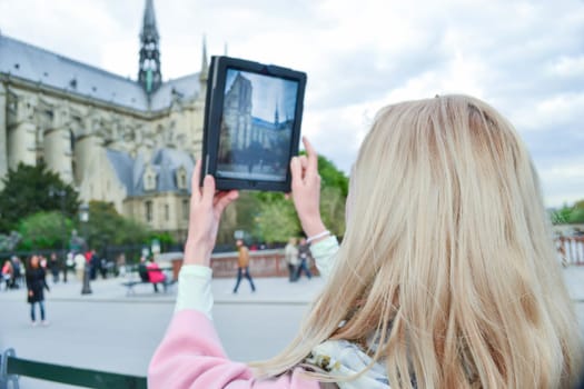 Blonde woman tourist in Paris making selfie with Notre-Dame cathedral