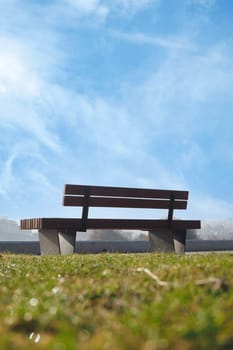 A serene wooden bench sits on lush grass under a clear blue sky, ideal for relaxation