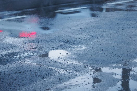 A moody and atmospheric urban scene featuring reflections on the rainsoaked pavement below