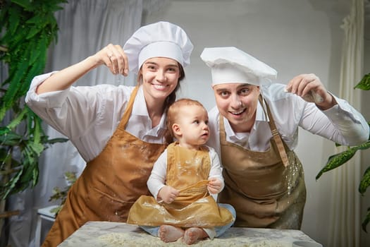 A family enjoys a fun cooking session, playfully covered in flour while engaging with their little ones in warm kitchen