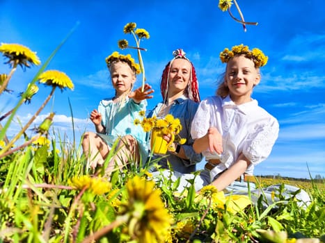 Three individuals, including two children, joyfully collect dandelions in a sunny field, capturing the essence of spring.