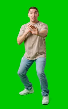 Man expressing fear while standing against a bright green background in studio