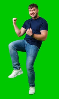 A strong man with fists raised, smiling confidently, on a bright green background in studio