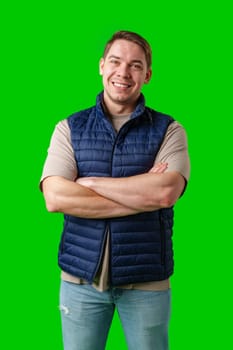 Confident man in a navy vest and t-shirt poses with crossed arms against a bright green background in studio