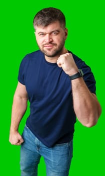 A strong man with fists raised, smiling confidently, on a bright green background in studio