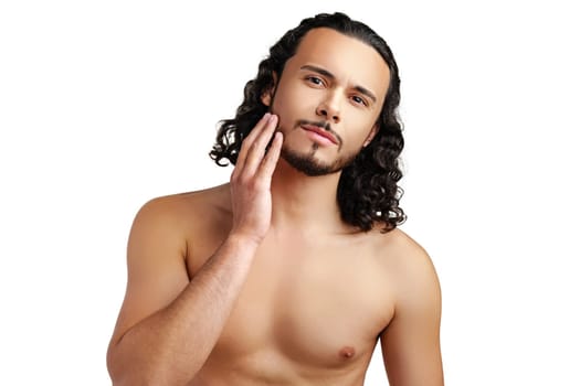 Young man with curly hair thoughtfully posing against a plain background in a studio setting