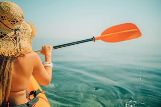 Woman in kayak back view. Happy woman with long hair in a swimsuit and hat floating in kayak on the sea. Summer holiday vacation. Summer holidays vacation at sea