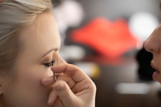 A closeup of a makeup artist applying false lashes to a bride before her wedding, ensuring she looks her best
