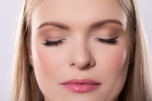 A glamorous closeup photograph of a woman showcasing her stunning, sparkling makeup along with a serene expression