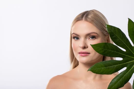 A stunning model elegantly showcases her natural beauty against a lush backdrop filled with green leaves