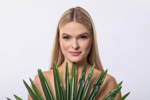 A stunning model with long hair holds vibrant green plants, beautifully embodying nature and harmony