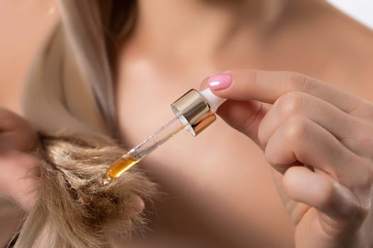 A stylish and fashionable woman carefully applying nourishing hair oil to achieve optimal hydration and shine