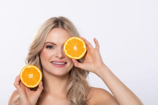 A cheerful woman happily poses with fresh orange halves in her hands, promoting a healthy and vibrant lifestyle