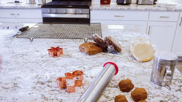 Using various festive cookie cutters, we're cutting out charming gingerbread cookies from the rolled dough on the sleek marble counter, bringing holiday cheer to the modern kitchen.