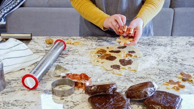 Using various festive cookie cutters, we're cutting out charming gingerbread cookies from the rolled dough on the sleek marble counter, bringing holiday cheer to the modern kitchen.